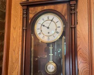 H. L. HUBBELL, BURL WALNUT WALL CLOCK, H 28", W 14" D 7.5':The H. L Hubbell wall clock has and enamel face, Roman numerals a two key wind and burl walnut accents. Marked "Made In Germany".