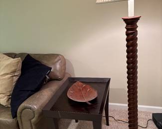 Black side table with pull-out tray, metal leaf tray, wood floor lamp and side arm of leather sectional
