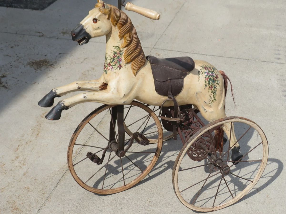 Lot 9. Antique wooden (?) horse tricycle with a cast iron frame, hand-painted details, leather saddle, and wooden wheels. Very good condition. Overall height is 33" with 16" wheels.