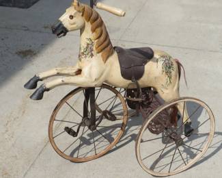 Lot 9. Antique wooden (?) horse tricycle with a cast iron frame, hand-painted details, leather saddle, and wooden wheels. Very good condition. Overall height is 33" with 16" wheels.