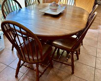 oak pedestal table with one leaf adapts from round to oval, & has 6 chairs.