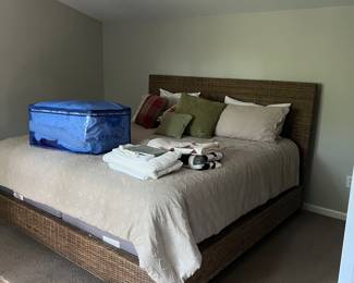 King sized bed with wicker frame and headboard, linen and pillows