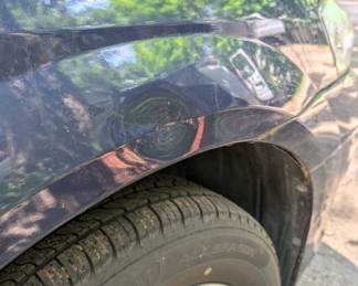 Small dent above front passenger tire wheel well