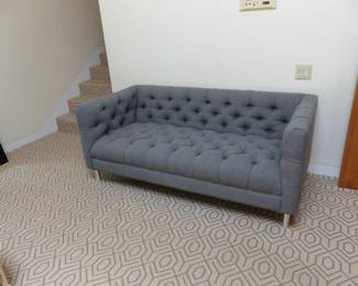 Gray tufted sofa with chrome legs