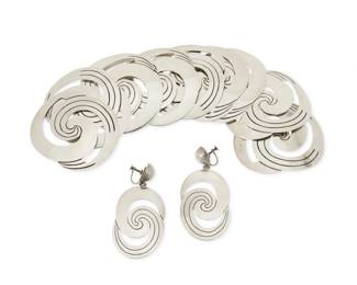 328
A set of Hector Aguilar silver conchos and earrings
Hector Aguilar (1905-1986)
Circa 1948-1962; Taxco, Mexico
One earring stamped: HA [conjoined] / .940 / Taxco / Mexico; conchos unmarked
Comprising ten silver scrolled openwork conchos and a pair of matching concho earrings, 12 pieces
Each concho: 2.375" H x 2.75" W; Earrings: 2.75" H x 1.375" W
221.2 grams
Estimate: $300 - $500