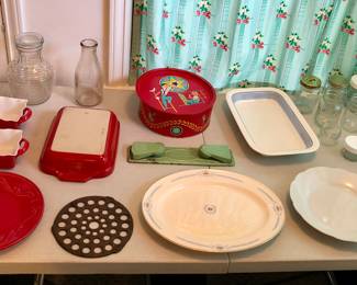 Red Emile Henry casserole dish, cast iron pot driver, ribbed glass carafe with lid, red tin, Arabia platter, silicone rolling pin