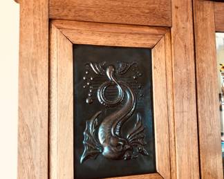 Copper inset of mythical sea creature on armoire