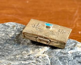 This lot features a vintage Native American pill box, made of sterling silver with a Turquoise center stone. Marked sterling with a total approx. weight of 8.55 grams and measures 1.5” W x 1” D.
