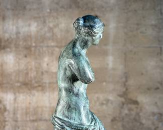 This lot features a famous replica of the Venus de Milo, one of the most famous ancient Greek sculptures. Made in Spain with maker mark near bottom as shown in photos. This sculpture is believed to be made of a hollowed bronze and measures, 24” H x 7.5” W x 7.5” D. The Venus de Milo is a masterpiece of Hellenistic sculpture and is renowned for its idealized beauty and enigmatic appeal, partly due to its missing arms.
