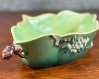 This lot features a Roseville Apple Blossom double handle vase in good overall condition with maker mark present underneath as shown in photos. This vase measures, 3” H x 15.5” W x 8” D.
