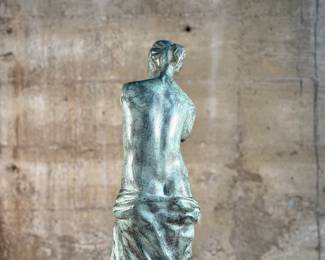 This lot features a famous replica of the Venus de Milo, one of the most famous ancient Greek sculptures. Made in Spain with maker mark near bottom as shown in photos. This sculpture is believed to be made of a hollowed bronze and measures, 24” H x 7.5” W x 7.5” D. The Venus de Milo is a masterpiece of Hellenistic sculpture and is renowned for its idealized beauty and enigmatic appeal, partly due to its missing arms.
