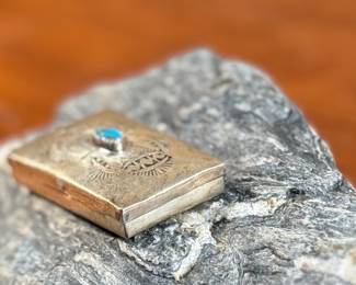 This lot features a vintage Native American pill box, made of sterling silver with a Turquoise center stone. Marked sterling with a total approx. weight of 8.55 grams and measures 1.5” W x 1” D.
