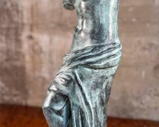 This lot features a famous replica of the Venus de Milo, one of the most famous ancient Greek sculptures. Made in Spain with maker mark near bottom as shown in photos. This sculpture is believed to be made of a hollowed bronze and measures, 24” H x 7.5” W x 7.5” D. The Venus de Milo is a masterpiece of Hellenistic sculpture and is renowned for its idealized beauty and enigmatic appeal, partly due to its missing arms.
