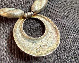 This lot features a beautiful sterling silver necklace with pendant by designer, Avi Soffer. Marked as shown in photos and measures, 18” with a total approx. weight of 48.00 grams. Avi Soffer is an Israeli jewelry designer known for his international perspective and commitment to social impact. He apprenticed with jewelry makers in Israel and Denmark, developing a unique design aesthetic. Soffer is actively involved in supporting human rights causes, including empowerment programs for Arab women in Israel and volunteering at a refugee center. He also mentors new artisans and employs individuals with disabilities in his workshop.
