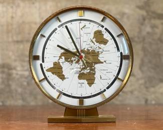 This lot features a Kundo Kieninger & Obergfell world clock, made in West Germany circa 1960s. This clock features quartz movement, elegant gold and white clock face, and a sleek brass case. The clock is designed to allow one to quickly calculate the time in any area of the world. In good working condition and measures, 10” H x 9” W x 4” D.
