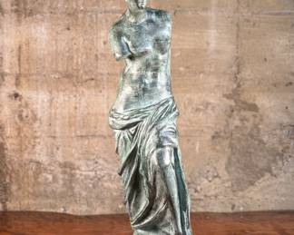 This lot features a famous replica of the Venus de Milo, one of the most famous ancient Greek sculptures. Made in Spain with maker mark near bottom as shown in photos. This sculpture is believed to be made of a hollowed bronze and measures, 24” H x 7.5” W x 7.5” D. The Venus de Milo is a masterpiece of Hellenistic sculpture and is renowned for its idealized beauty and enigmatic appeal, partly due to its missing arms.
