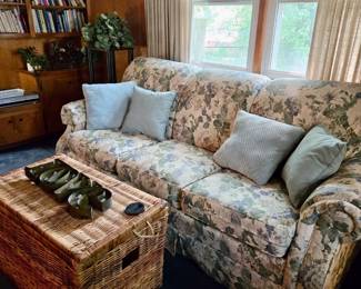 Floral Upholstered Sofa with Decorative Pillows; Wicker Trunk; LOVE Sign; Plant Stand; Silk Plants; Books
