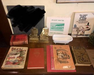 Old books including 1890 “Zig Zag Journeys in the Great Northwest”, vintage Puget Sound ferry poster, brass ship bookends, salesman sample cast iron bathtub