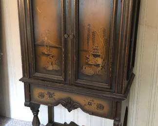 Vintage cabinet on legs with painted Asian/tropical scenes on doors (60”H, 17”D, 34”W)