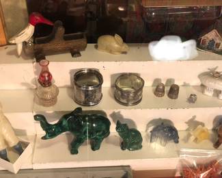 More case items: celluloid baseball player, carved stone elephants, silver napkin rings, sterling thimbles, Los Angeles ceramic Zeppelin (broken), cast iron woodpecker toothpick holder