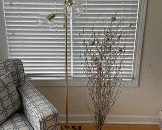 Festive display of metallic branches and triple gold floor lamp