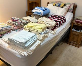 Twin bed with assorted bed linens and quilts