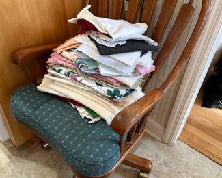 Wooden dining chair with green cushion and stack of linens