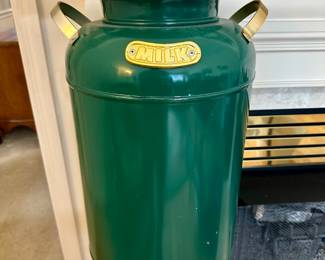 Antique green metal butter churn with lid and handle, marked "B-K", resting on a white ceramic base; rustic farmhouse decor piece.