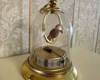 Vintage anniversary clock under glass dome with brass base and rotating pendulum; classic decorative timepiece.