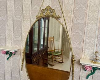 Elegant oval mirror with gold frame, rope hanger and matching pouch; stylish vintage wall decor.