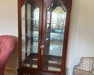 Tall wooden curio cabinet with glass doors and shelves, elegant cabriole legs and decorative crown; ideal for displaying china or collectibles.