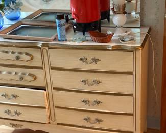Dresser with mirror (1 of 2 pieces), coffee maker, vase with flowers.