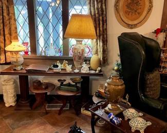 Lots of side tables, lamps, wall art, two wing back leather chairs.