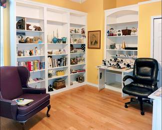 Office filled with books, glassware and objects d'art.