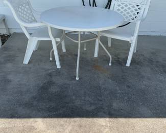 White outdoor table and chairs. Chairs are plastic, table top is fiberglass with metal legs.