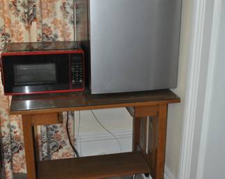 Dorm size refrigerator , microwave, small library table and a firkin