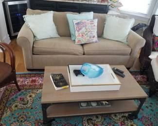 Neutral loveseat; industrial chic coffee table on wheels; festive paisley rug