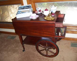 ANTIQUE MAHOGANY DOUBLE DROP LEAF TEA CART WITH PULL OUT GLASS SHELF, DRAWER AND BOTTOM SHELF  AND TEAA TEA RELATED STUFF ON TOP