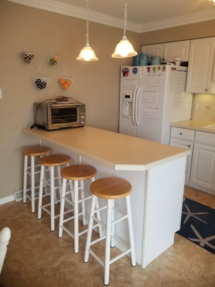 Tidy white L-shaped kitchen with peninsula