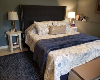 King bed with navy upholstered headboard; two end tables & table lamps