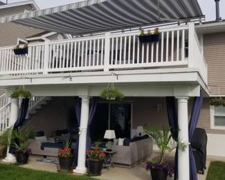 Electric awning with remote control; limited amount of vinyl railing; patio curtains; potted plants
