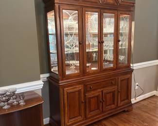 W9 - $250. Alexander Julian Lighted China Cabinet. Measures 61" wide x 18" deep x 85" tall. (Base is 32.5" Top is 53" tall) Has 2 glass shelves. Overall very good condition but does have minor signs of wear. Moves in two pieces.