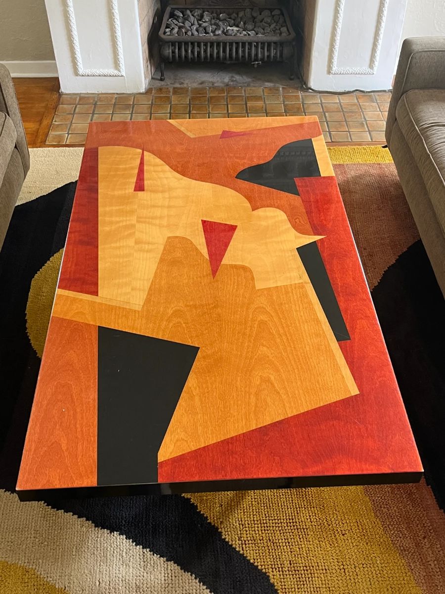 A striking one-of-a-kind tabletop by Benjamin Le for Axi Contemporary Furniture. This 20th-century piece features bold, geometric inlaid forms created with polychrome aniline-dyed woods in warm rust, ochre, black, and golden tones. The top is framed in a sleek black lacquered border, measuring approx. 64.75" L x 36.25" W x 2" D. A gallery-worthy surface that blends functional design with fine art sensibility—ideal as a dramatic table, desk, or wall-mounted installation.