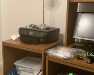 A desk with computer screen, key board, shredder and office supplies.