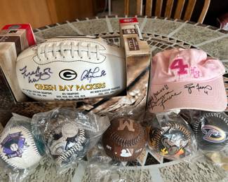 On the left - Green Bay Packers, title town football with a half a dozen Packers autographs.
On the right - both Deanna and Brett Farve signed pink #4 hat.