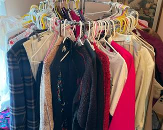 Lots of clothing from 30 to 60 years ago on several clothing racks.
