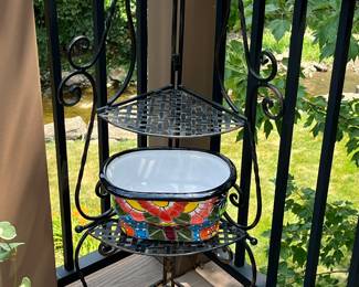 Black wrought iron corner shelf unit with colorful ceramic bowl