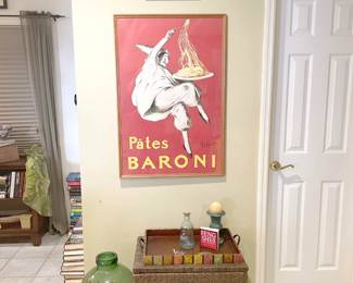 Poster art, glass jug filled with corks and wicker file cabinet on metal stand