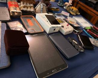 Assorted electronics and gadgets including tablet, smartphone, camera, and remote controls