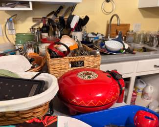 Collection of kitchenware including red and blue enamel cookware, baskets and assorted utensils